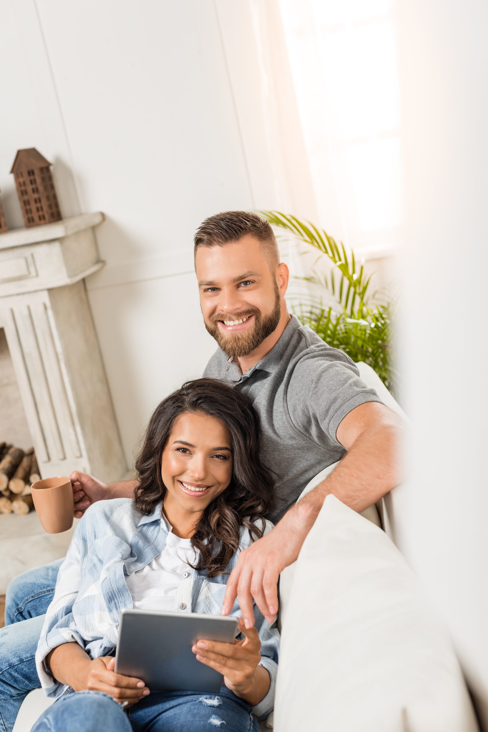 young smiling couple relaxing and using digital tablet at home